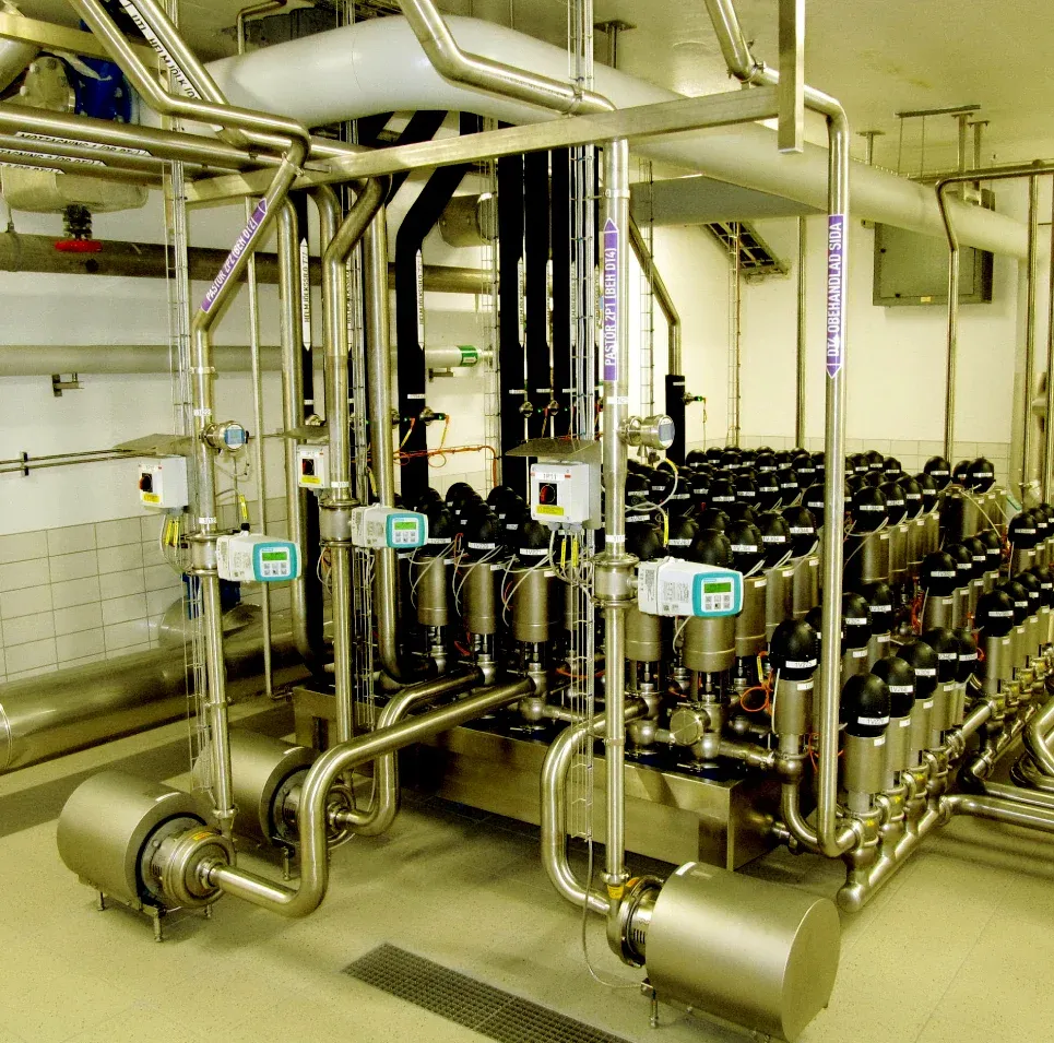Ventilpark med pumpar och rostfria rörsystem i ett mejeri